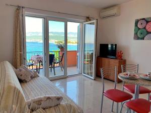 a bedroom with a bed and a table and a balcony at Apartments Beach in Šilo