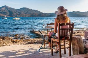 a woman sitting in a chair at a table by the water at Dream Boathouse in Klima