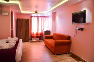 a living room with a couch and a tv on a wall at Hotel Runway Inn in Port Blair