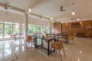 a dining room with tables and chairs and windows at KSTDC Hotel Mayura Kauvery KRS in Hosa Kannambādi