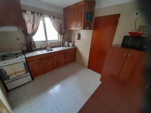 a kitchen with wooden cabinets and a sink and a stove at Sueños del Golfo in Puerto Madryn +7 photos