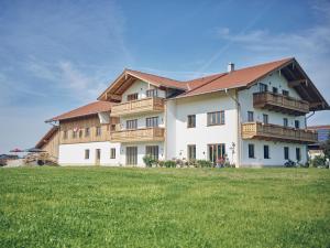 バート・アイブリングにあるLehnerhofの木製のバルコニーと緑の野原のある大きな家