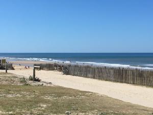 a sandy beach with a fence and the ocean at Les Pieds dans l'Eau in Lacanau-Océan