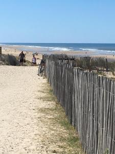 una valla en la playa con gente caminando por la playa en Les Pieds dans l'Eau en Lacanau-Océan