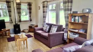 a living room with a purple couch and a tv at Foxglove Cottage in Maybole
