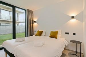 a bedroom with a large white bed with yellow pillows at Eb in De Panne