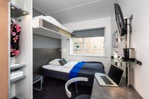 a small room with a bed and a desk with a laptop at Cabinn City in Copenhagen