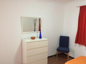 プラヤ・デル・イングレスにあるApartamentos Beatrizのベッドルーム(ドレッサー、青い椅子付)