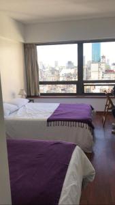 two beds in a hotel room with a large window at RANCHO TANGUERO EN EL OBELISCO en Corrientes 818 in Buenos Aires