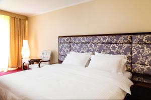 ベルツクにあるMOROZOVO Resort-Hotel&SPAのベッドルーム(青いヘッドボード付きの白い大型ベッド1台付)