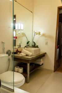 a bathroom with a sink and a toilet and a mirror at Pousada Ponta da Vigia in Penha