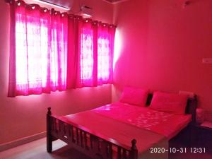 a pink bedroom with a bed with a window at Aruvi Hotel in Yelagiri