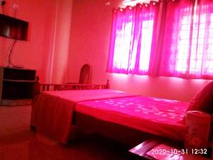 ein rotes Schlafzimmer mit einem Bett und einem Fenster in der Unterkunft Aruvi Hotel in Yelagiri