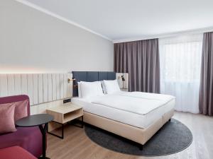 a hotel room with a bed, chair, and nightstand at Crowne Plaza Hamburg City Centre, an IHG Hotel in Hamburg