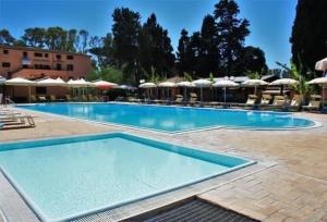 a large swimming pool in a resort with umbrellas at La Pineta Dei Liberti in Lido dei Pini
