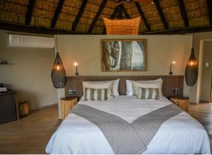 1 dormitorio con 1 cama grande con sábanas y almohadas blancas en Laluka Safari Lodge - Welgevonden Game Reserve, en Reserva de Welgevonden