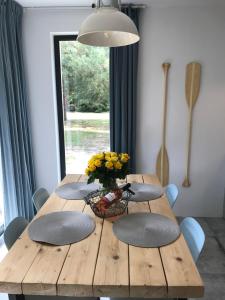 una mesa de madera con 4 sillas y un jarrón de flores en Sosnowe Zacisze, en Sasino