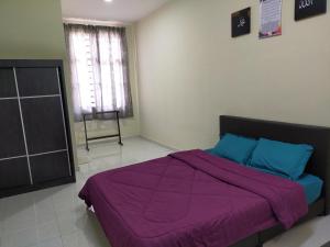 a bedroom with a bed with purple sheets and a window at Fathi Homestay, Pagoh Jaya in Pagoh