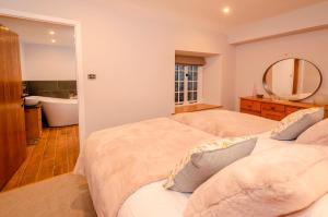 a bedroom with two beds and a bathroom with a tub at Juniper Cottage, Chapel Stile, Langdale in Chapel Stile