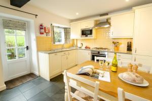 a kitchen with a wooden table and a dining room at Pippins, Elterwater in Chapel Stile