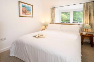 a bedroom with a white bed and a window at Pippins, Elterwater in Chapel Stile