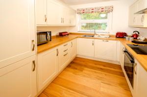 a kitchen with white cabinets and a wooden floor at Quarry Bank in Chapel Stile