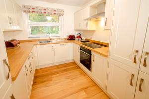 a kitchen with white cabinets and a sink and a window at Quarry Bank in Chapel Stile