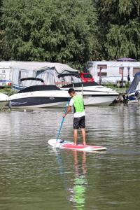 a man on a paddle board in the water at Kormorán tóparti szobák in Katalinmajor
