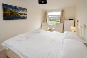a white bedroom with a large bed and two chairs at 27 Thrang Brow, Chapel Stile in Chapel Stile