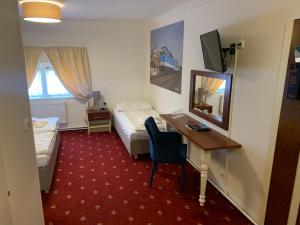 Habitación de hotel con escritorio, cama y espejo en City-Inn, en Praga