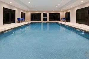 a large swimming pool in a hotel with blue chairs at Holiday Inn Express & Suites - Fayetteville by IHG in Fayetteville