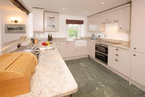 a kitchen with white cabinets and a wooden counter top at End Cottage, Chapel Stile in Chapel Stile +12 photos