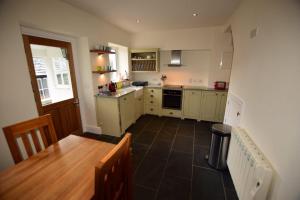 a kitchen with a wooden table and a kitchen with a counter top at Farra Grain, Little Langdale in Little Langdale