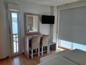 a bedroom with a table and chairs and a television at Hotel a Muradana in Muros