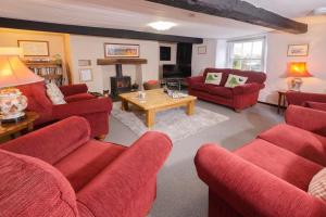 a living room with red couches and a fireplace at Stickle Cottage, Great Langdale in Grasmere