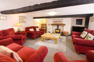 een woonkamer met rode banken en een open haard bij Stickle Cottage, Great Langdale in Grasmere