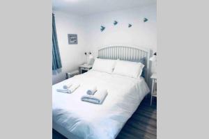 戈尔韦Fuchsia Apartment Tranquil Modern Seaside Apartment on the Wild Atlantic Way的卧室里有一张白色的床，床上有两条毛巾