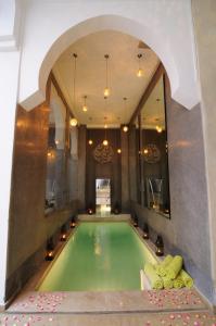 een zwembad in een kamer met een grote spiegel bij Riad Chayma Marrakech in Marrakesh