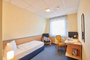 a hotel room with a bed and a desk at Hotel Zum Grunewald in Dinslaken