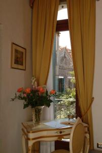a vase of flowers on a table in front of a window at Apostoli Palace in Venice