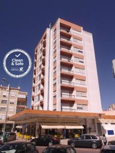 un edificio alto con coches estacionados frente a él en Residencial Jardim da Amadora, en Amadora