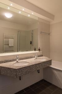 a bathroom with two sinks and a large mirror at Hotel König Ludwig II in Garching bei München