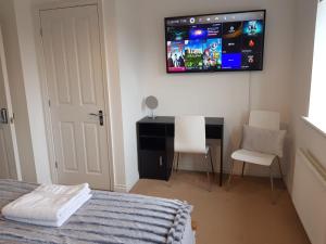 Ladysmith House - 4 Bedrooms - Full House في غريمسبي: غرفة نوم مع سرير وتلفزيون على الحائط