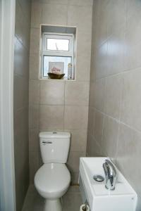 La salle de bains est pourvue de toilettes, d'un lavabo et d'une fenêtre. dans l'établissement Wilmington Lodge Dartford London, à Kent