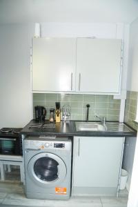 a kitchen with a washing machine and a sink at Wilmington Lodge Dartford London in Kent