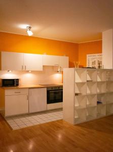 uma cozinha com paredes cor de laranja e armários brancos em Cozy Domicile Leipziger Auwald em Leipzig
