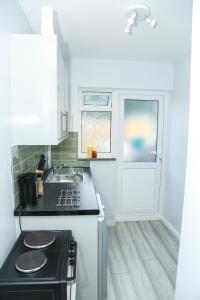 a small kitchen with a stove and a sink at Wilmington Lodge Dartford London in Kent