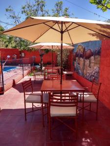 a patio with tables and chairs and an umbrella at Cabañas y Hostal Las Marias in Cafayate