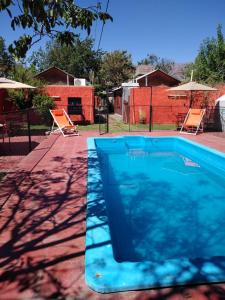 a blue swimming pool with two chairs and a fence at Cabañas y Hostal Las Marias in Cafayate