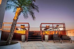 a resort with two decks with chairs and a palm tree at Pousada Conca di Mare - Restaurante - Pé na areia com serviço de praia in Bertioga